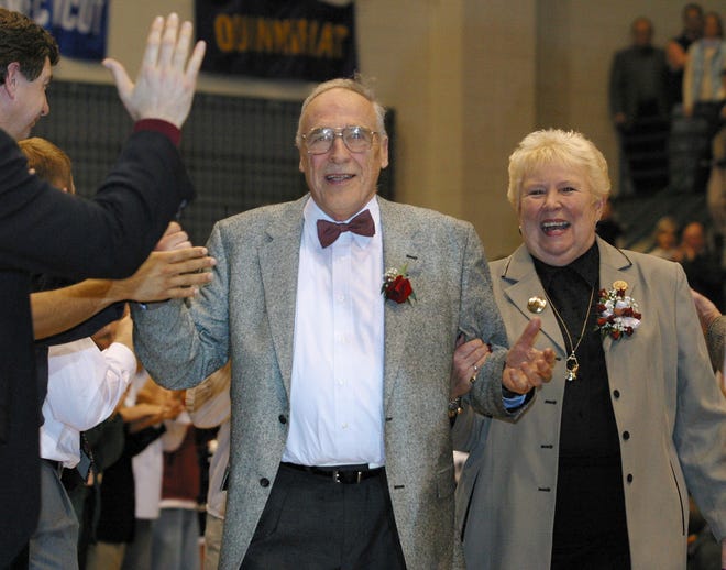 FILE - Mount St. Mary's men's NCAA college basketball coach Jim Phelan and his wife Dottie walk through a gauntlet of former players at Knott Arena in Emmitsburg, Md., after Phelan coached his last game as coach, in this Saturday, March 1, 2003, file photo. Phelan, the bow-tied basketball coach who won 830 games during nearly a half-century at Mount St. Mary's, has died. He was 92. The athletic department at Mount St. Mary's said Phelan died in his sleep at home Tuesday night, June 15, 2021. (AP Photo/Timothy Jacobsen, File)