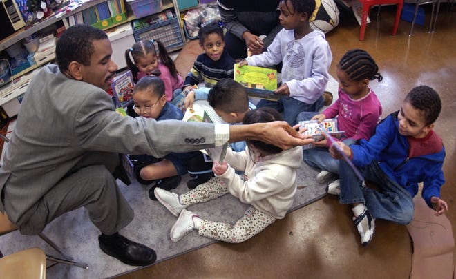 Rochester city school board member Malik Evans hands out books to students at George Mather Forbes School 4 in 2005.