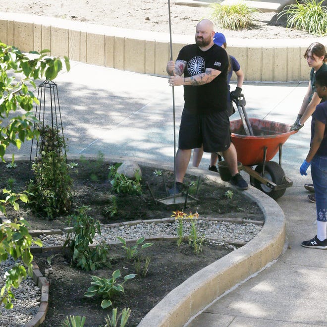 Dan Coffield places a pole for a totem in the courtyard of the University of Akron’s Schrank Hall on Thursday.
