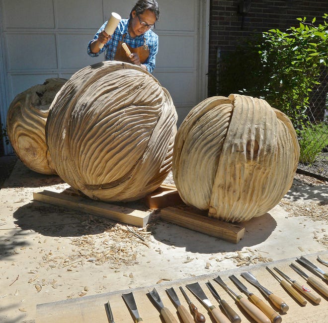Artist Fredy Huaman Mallqui works on his sculpture "Together" on Wednesday, in the driveway of his Erie home. The piece is one of 13 selected for the new Downtown Erie Sculpture Walk, with works to be installed through early July.