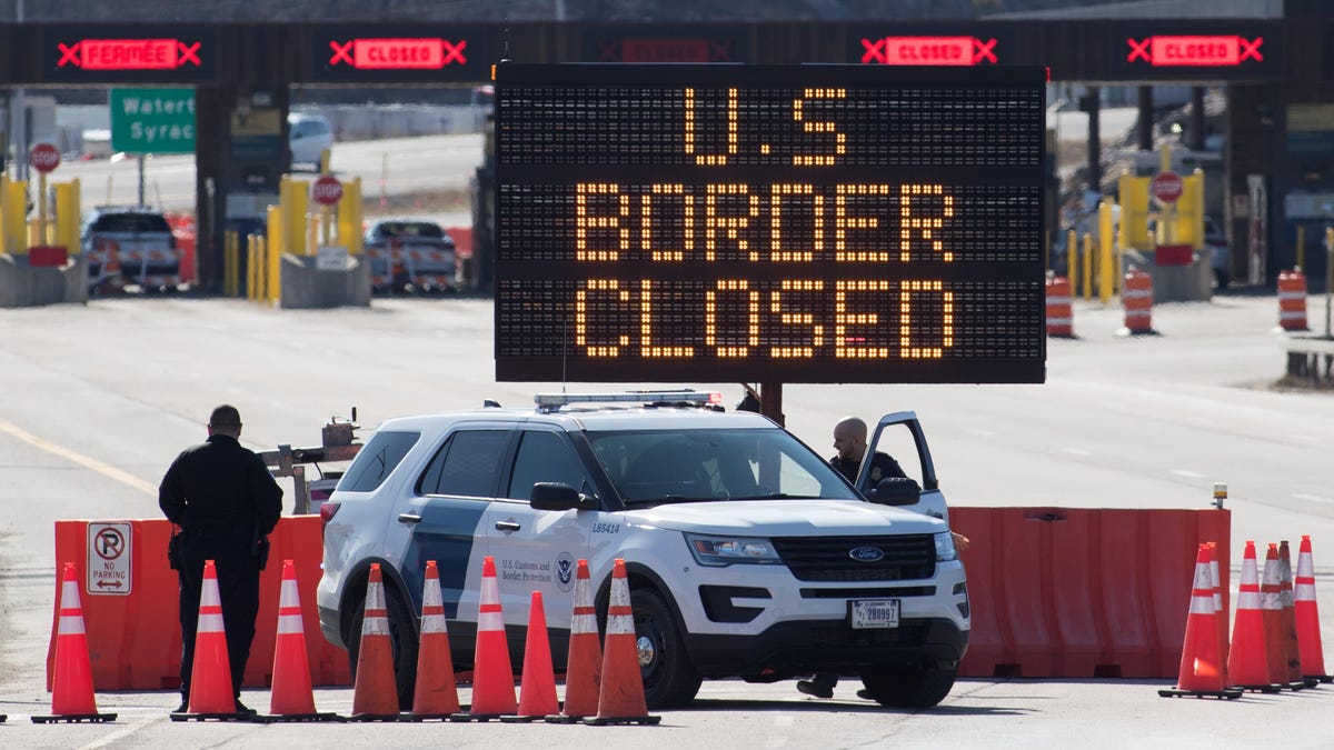 U.S. Customs officers stand beside a sign saying that the U.S. border is closed at the U.S./Canada border in Lansdowne, Ontario, on March 22, 2020.