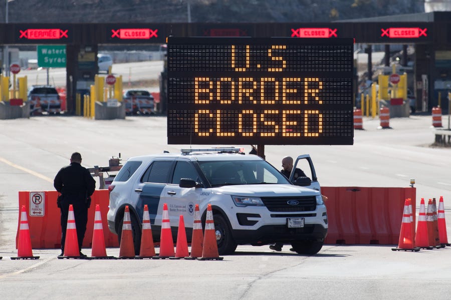 U.S. Customs officers stand beside a sign saying that the U.S. border is closed at the U.S./Canada border in Lansdowne, Ontario, on March 22, 2020.