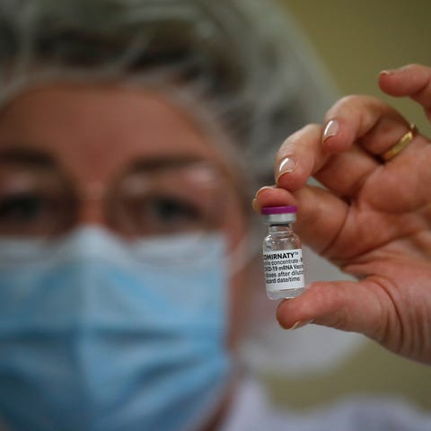 An employee holds a vial of COVID-19 vaccine in th