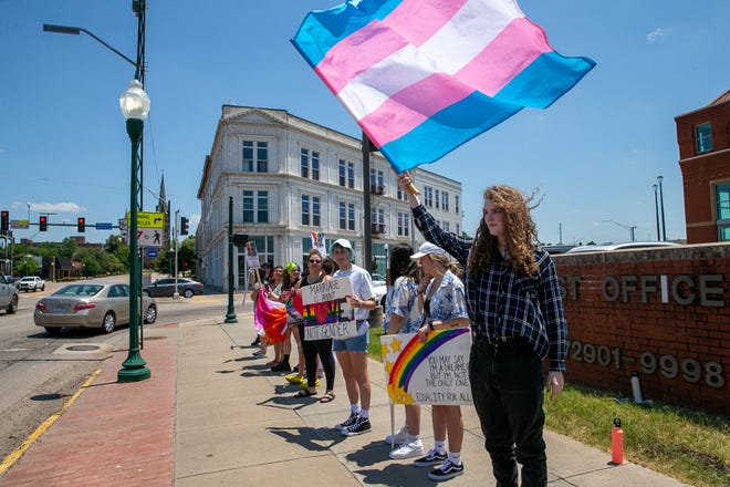 Phoenix Blair holds a colorful flag representing the transgender community at the Rally for Equality in front of the U.S. Post Office on Garrison Avenue in Fort Smith, Sunday, June 20, 2021.