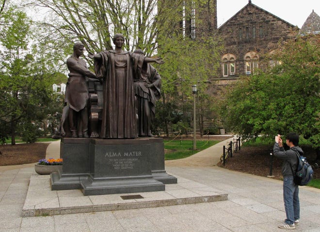 In this April 28, 2014 photo, a University of Illinois student takes a photo of the popular Alma Mater statue on campus in Urbana, Ill.  (AP Photo/David Mercer)