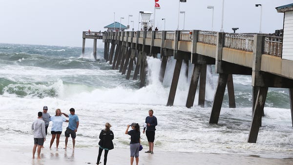 Visitors take pictures with the rough surf at the 
