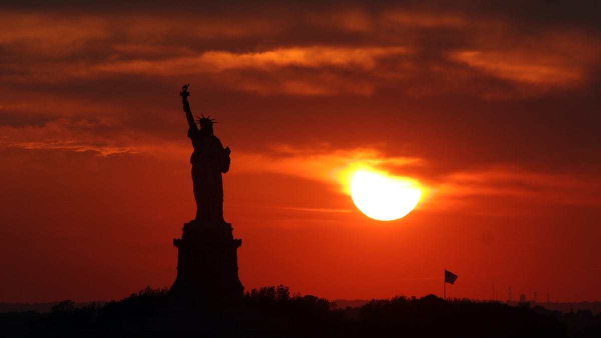 In this file photo from Wednesday, June 21, 2006, the sun sets behind the Statue of Liberty in a view from New York on the summer solstice, the longest day of the year.