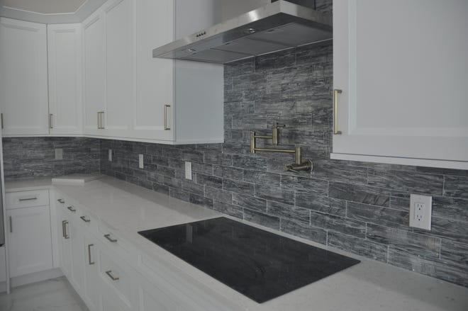 The kitchen in the new spec home showcases a backsplash made of glass. It looks like tile, but it is actually colored glass. The same backdrop is used across the room behind the bar area.
