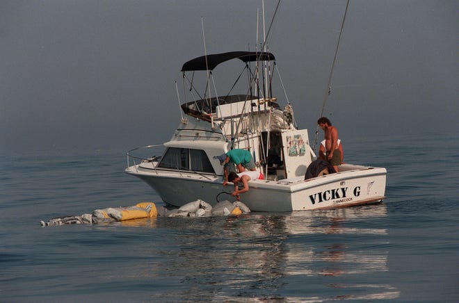 Eine Gruppe von Männern in einem privaten Boot versucht, ein scheinbar Rettungsfloß zu schleppen, das zwischen den Trümmern des TWA-Absturzes am Donnerstag, 18. Juli 1996, schwimmt. Viele Privatfahrzeuge halfen bei der Suche.  .