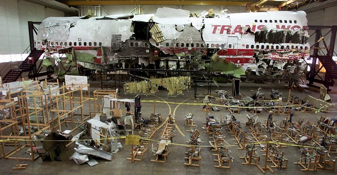 In diesem Aktenfoto vom 16. Juli 2001 befinden sich die Sitze, der Vordergrund und das Wrack von TWA-Flug 800 in einem Hangar in Calverton, New York.  Die Katastrophe vom 17. Juli 1996 war eine der berüchtigtsten Luftkatastrophen der Geschichte.  Einige diskutieren noch immer über die Feststellung, dass die Boeing 747 durch eine Explosion des zentralen Kraftstofftanks, die durch einen Funken aus einem Kurzschluss gezündet wurde, zum Absturz gebracht wurde;  eine Schlussfolgerung, die erreicht wurde, nachdem der zerfallene Jet wie ein Puzzle mühsam wieder zusammengesetzt wurde.