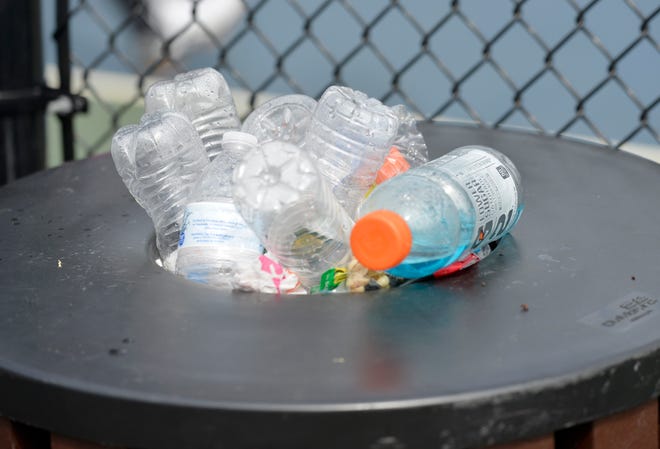 Plastic bottles overflow from a trash can at pickle ball courts in Mashpee.
