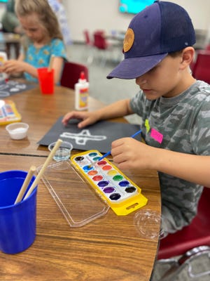 A youth paints in an arts and crafts area at "Summer ViBeS" at First Christian Church (Disciples of Christ) of Edmond .