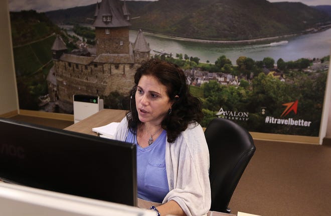 Rose Cacciatore, senior leisure travel consultant, helps a client while on duty at Travel Leaders Framingham, June 25, 2021. Behind her is a mural of the Rhine River flowing through Koblenz, Germany.