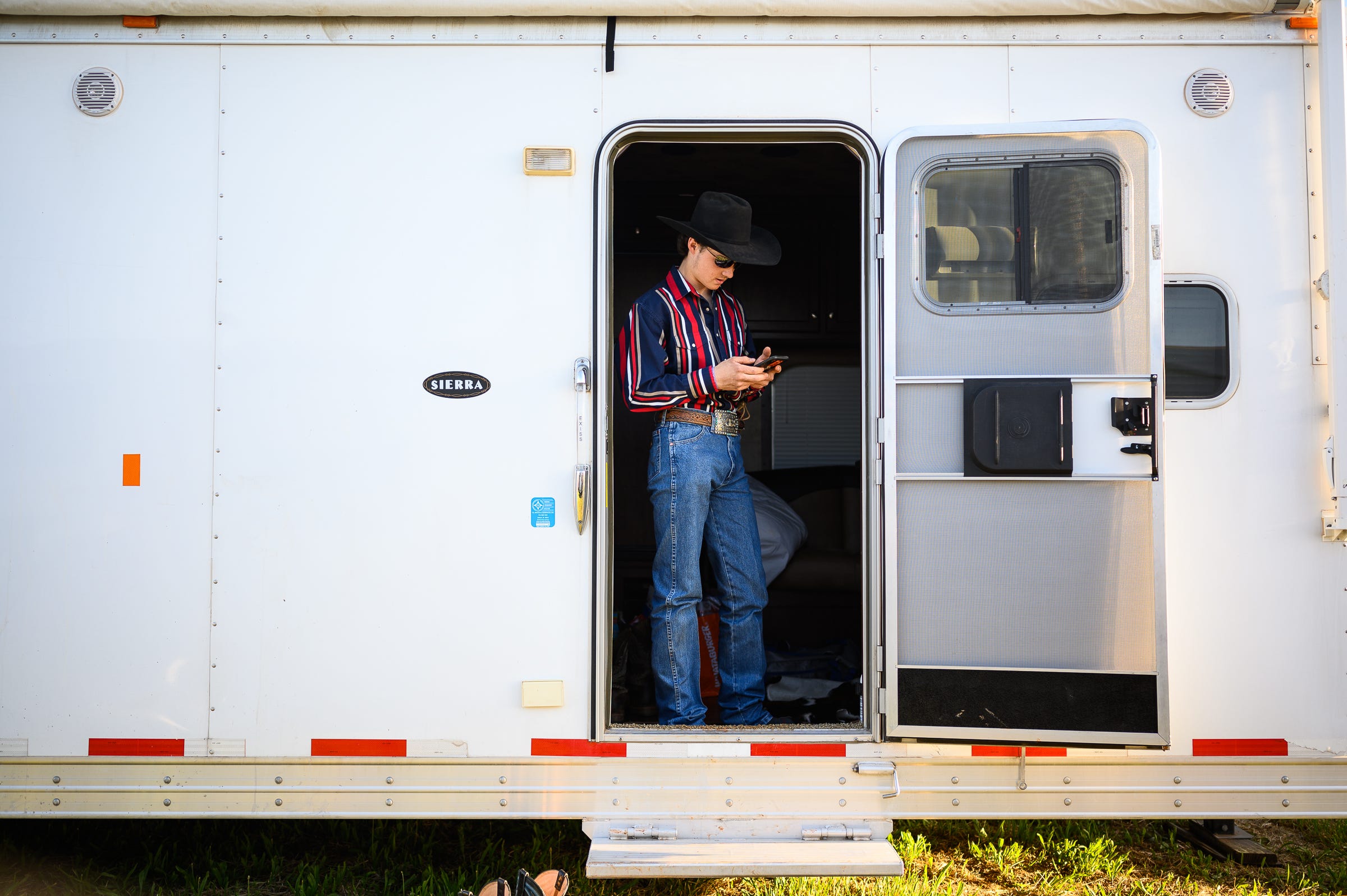 Colton checks his phone in his trailer before competing