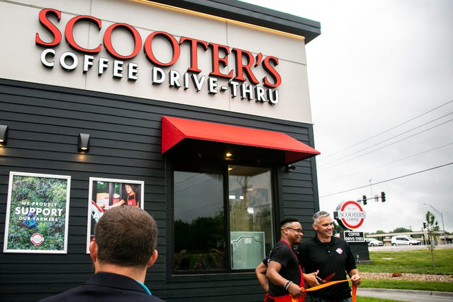 Scooter's Coffee store manager Kevin Wood, left, and franchise owner Mark Holtkamp, of Solon, pose for a photo a ribbon during the grand opening, Friday, June 25, 2021, at 1335 Highway 1 in Iowa City, Iowa. The store is the first franchise of the Nebraska-based company in Iowa City.