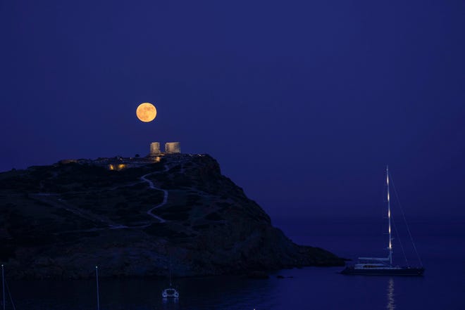 The strawberry full moon rises behind the ancient marble temple of Poseidon at Cape Sounion, about 45 miles south of Athens, Greece, on  June 24, 2021.