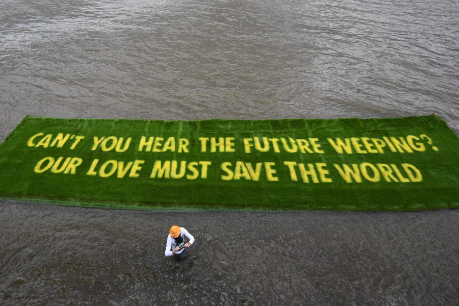 Extinction Rebellion activists set afloat an environmental message grown on a carpet of living grass, telling governments to act in the lead-up to the COP26 climate change summit, on the River Thames on June 25 in central London.