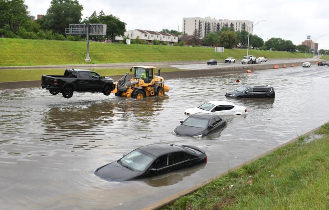 A truck is hoisted from Interstate 75 and Canfield Street as heavy rain flooded streets in Metro Detroit on Saturday, June 26, 2021.
