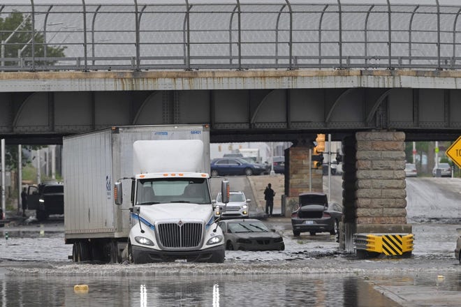 A semi tractor maneuvers through a flooded Michigan Avenue at Scotten Street in Detroit on Saturday, June 26, 2021.