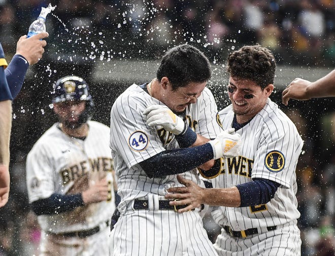 Brewers first baseman Keston Hiura (middle)  celebrates with third baseman Luis Urias after driving in the winning run with a sacrifice fly in the eleventh inning Friday.