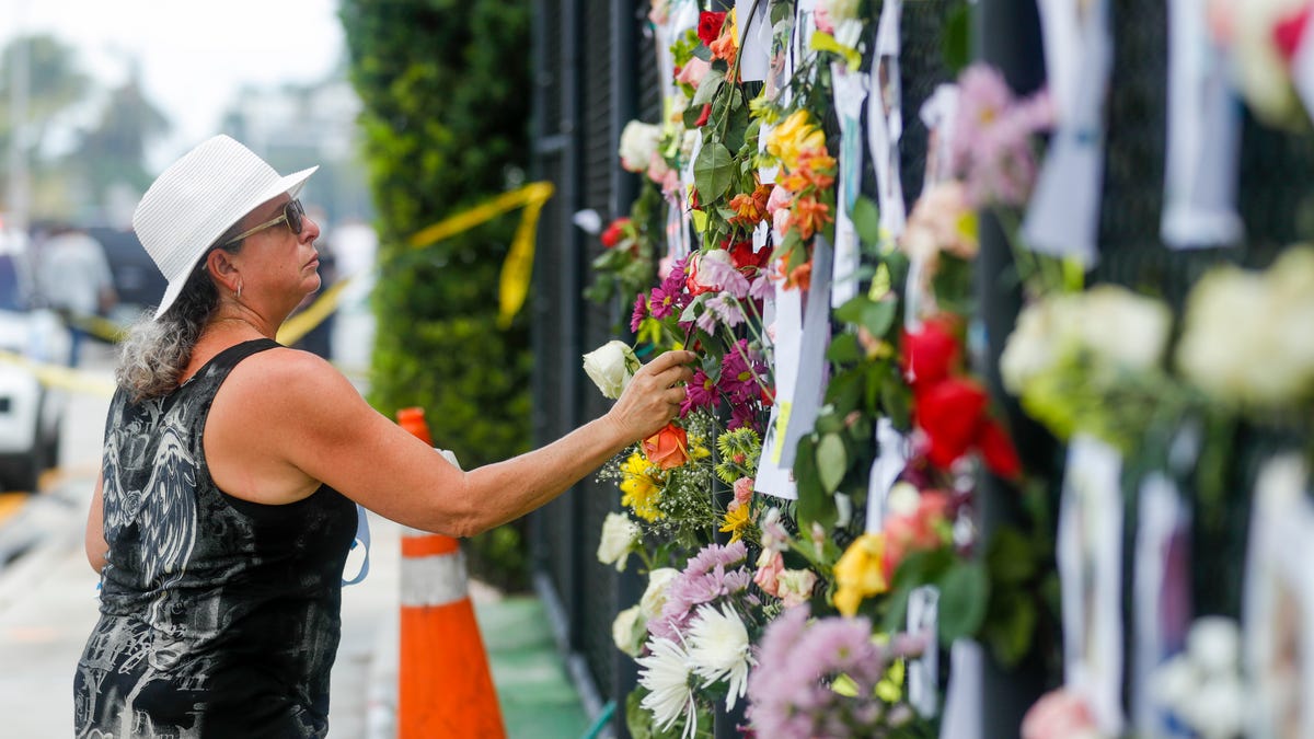 Nora Estevez adds a rose to a make-shift memorial near the site where a 12-story building partially collapsed in the community of Surfside, Florida on June 26, 2021. 