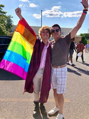 Bryce Dershem and his father proudly carry his Pride flag upon graduation. During the ceremony, Dershem was asked to remove his flag.