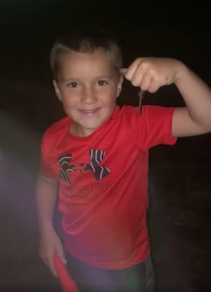 Kacin Strong holds up a nightcrawler he found at Lemon Park last week, after a significant rainfall brought the large worms up to ground-surface.