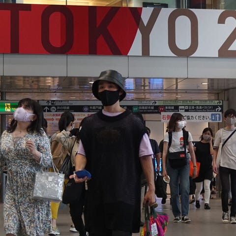 People wearing face masks walk on a concourse at a