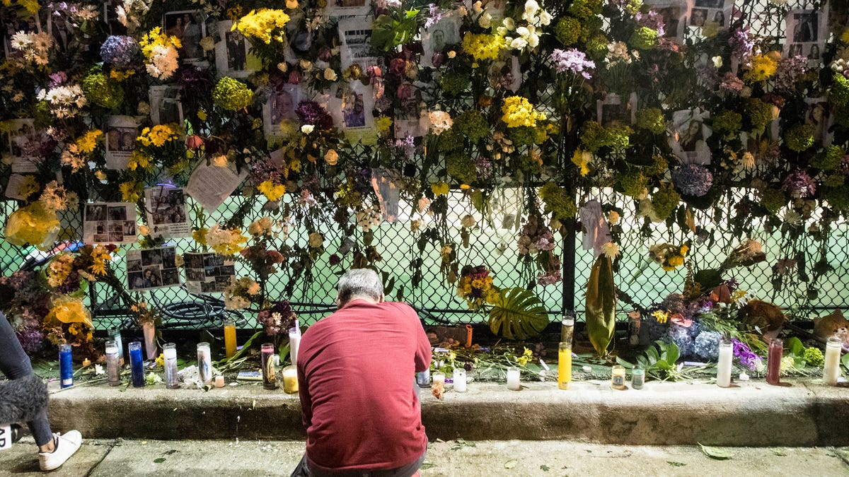 A man kneels at the memorial wall of those missing in the Champlain Towers collapse in Surfside, Fla on Monday, June 28, 2021.