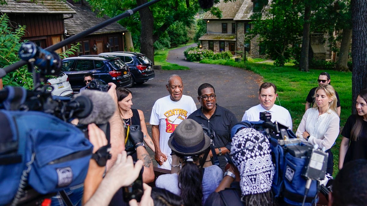 Bill Cosby, center, and spokesperson Andrew Wyatt, right, approach members of the media gathered outside the home of the entertainer in Elkins Park, Pa., Wednesday, June 30, 2021. Pennsylvania's highest court has overturned comedian Cosby's sex assault conviction. The court said Wednesday that they found an agreement with a previous prosecutor prevented him from being charged in the case. The 83-year-old Cosby had served more than two years at the   state prison near Philadelphia and was released.