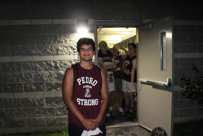 Algonquin senior Pedro Ribiero wears a "Pedro Strong" t-shirt outside of the T-Hawks locker room at Russell Field in Cambridge as his teammates look on.