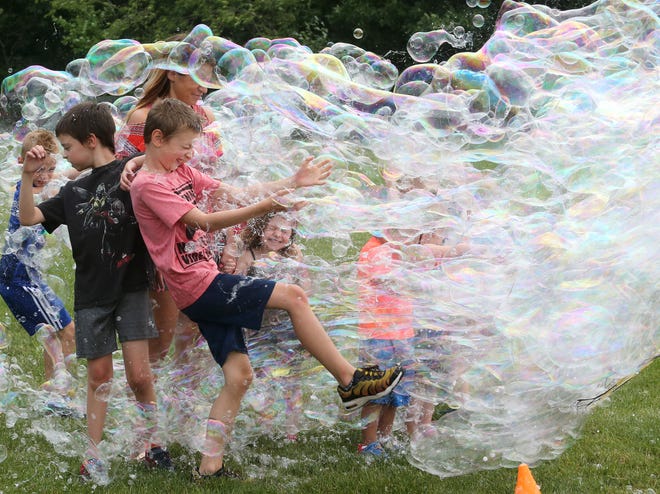 Children brace for a surge of bubbles during Freedom Fest at Boettler Park in Green on Saturday, June 26, 2021. Gary Pearlman, better known at "Dr. U.R. Awesome," provided the bubbles for the event.