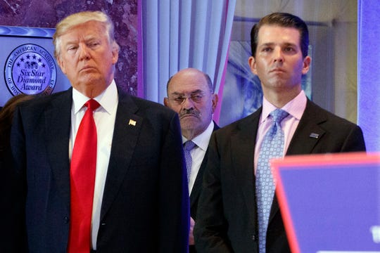 Allen Weisselberg stands between President-elect Donald Trump and Donald Trump Jr. in the lobby of Trump Tower in New York on Jan. 11, 2017.
