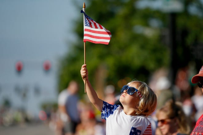 Reid Barnes waves an American flag last July during the LibertyFest Parade in celebration of the Fourth of July in Edmond.