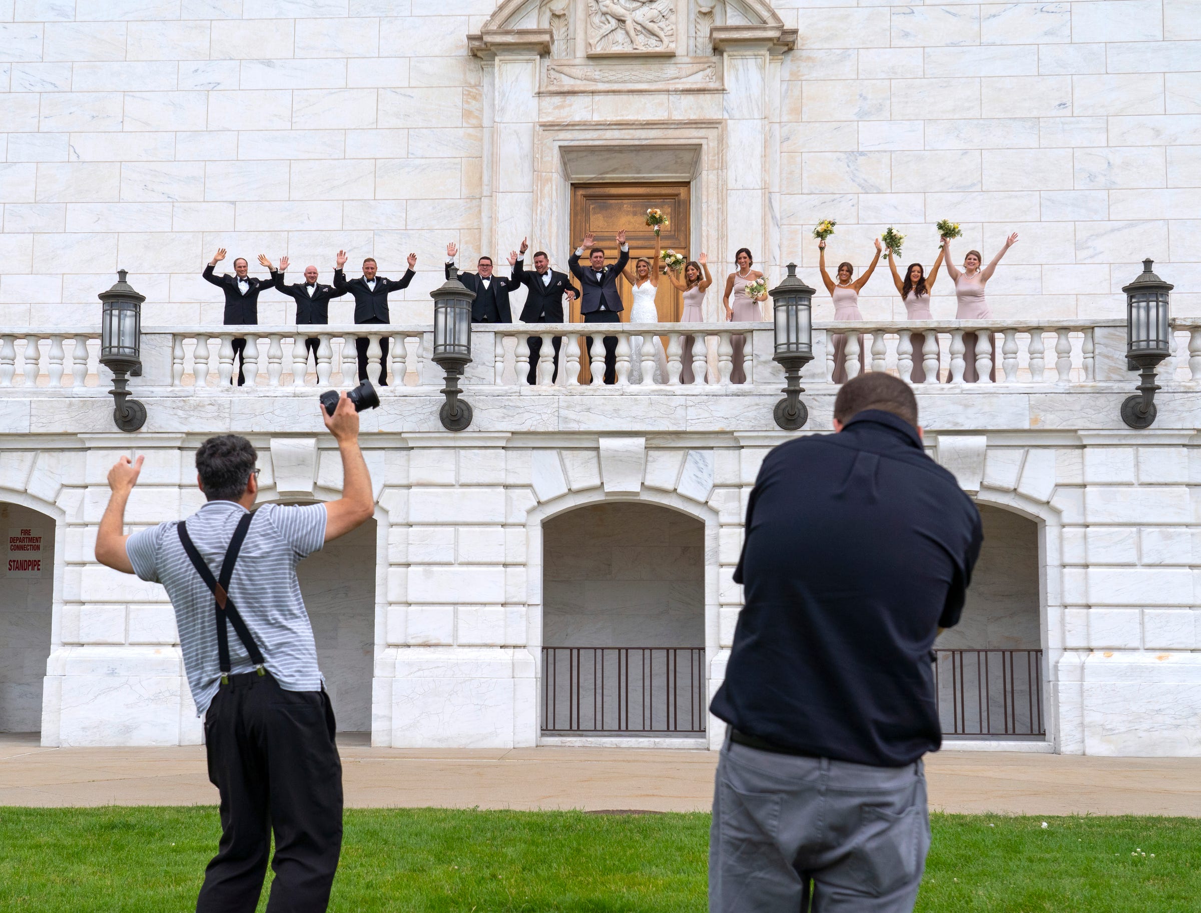 Photographer Arthur Safarov demonstrates a dance to get Sean McNally and his wife, Rebecca McNally, to do while having their photo taken with their wedding party on the staircase at the rear of the Detroit Institute of Arts on Saturday, June 19, 2021.