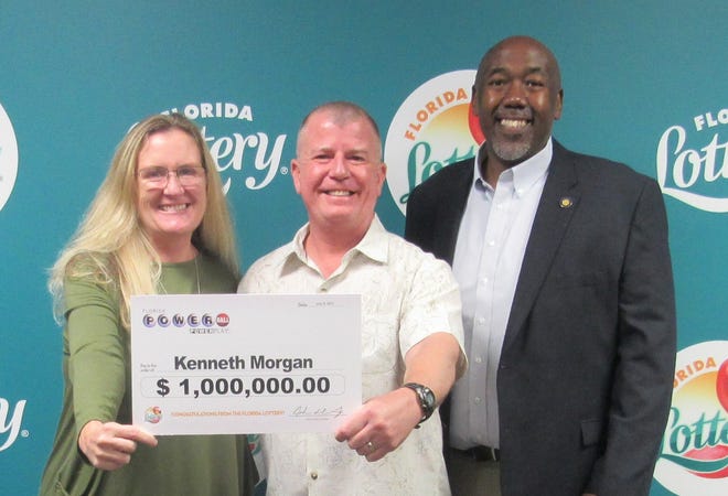Kenneth Morgan (center) poses with his wife and Florida Lottery Chief of Staff Reggie Dixon after claiming a $1 million Powerball prize at the Tallahassee headquarters.