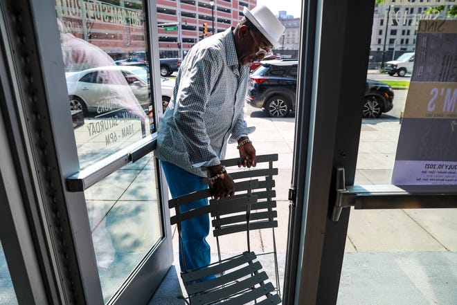 Hot Sam's co-owner Tony Stovall, 69, of Southfield places chairs and a table outside the store on July 7, 2021. Stovall says he wants people to come to the store for more than shopping. Hot Sam's Detroit is celebrating its 100th year of being in business in downtown Detroit and they'll be hosting a large event at Campus Martius and Cadillac Square this Saturday.