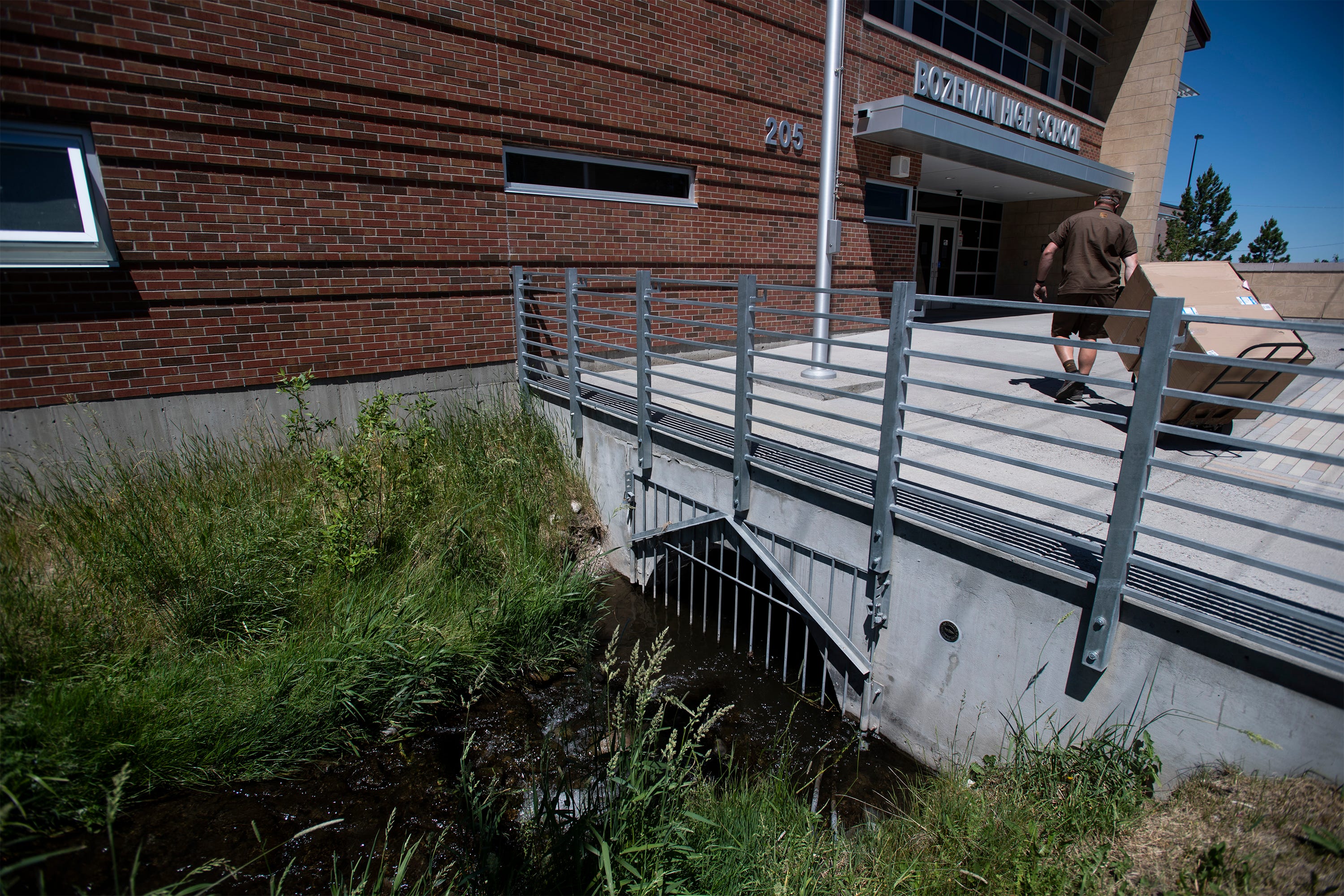 Water flows through an irrigation ditch and under an entrance to Bozeman High School in Bozeman, Mont., on June 16, 2021.