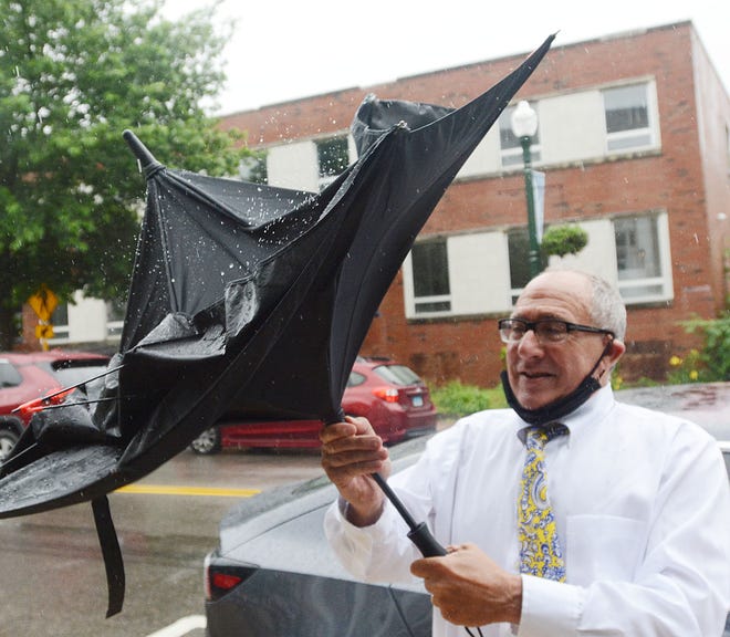 Bart Sayet of Norwich repairs his partially wind-damaged umbrella in downtown Norwich Friday as Tropical Storm Elsa passes through the area. Sayet said of the rain "It's a storm. We're used to it and the farmers say we need it." [John Shishmanian/ NorwichBulletin.com]