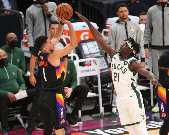 Phoenix Suns guard Devin Booker (1) shorts over Milwaukee Bucks guard Jrue Holiday (21) during Game 2 of the NBA Finals at Phoenix Suns Arena July 8, 2021.
