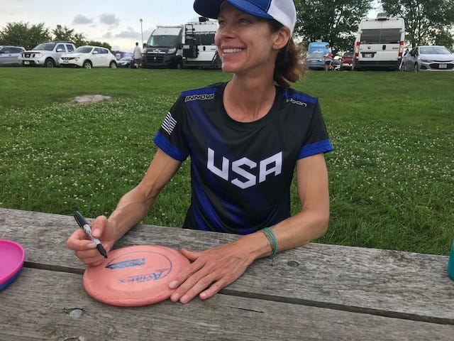 Five-time disc golf world champion Juliana Korver signs a disc for a fan at the Disc Golf Pro Tour event in Indianola, July 10, 2021. Korver designed the Indianola Pickard Park disc golf course which opened in 1999.