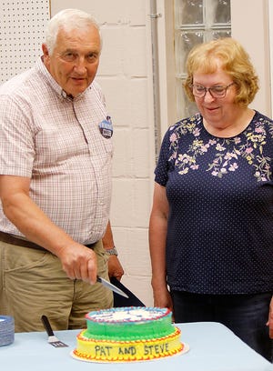 Retiring Ashland County Fair Manager Steve Englet and retiring Fair Treasurer Patricia Deane cut the cake at their surprise potluck in Mozelle Hall on Monday. TOM E. PUSKAR/TIMES-GAZETTE.COM