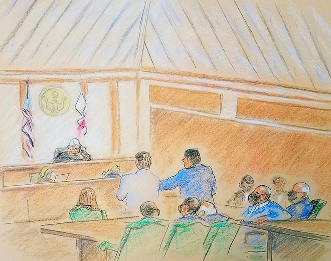 Defender Tim Jansen standing in a dark blue suit. Peter Nothstein, who will also stand before US District Judge Robert Hinkle in the bribery proceedings against JT Burnette on Monday, July 12, 2021. Burnette is sitting on the table next to Greg Kehoe, her hand relaxed.