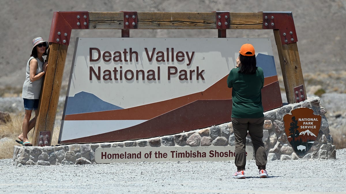 People pose for a photograph at the park entrance sign on July 11, 2021 in Death Valley National Park, California. An excessive heat warning was issued for much of the Southwest United States through Monday.