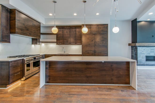 This Sylvan Park kitchen shows all-wood cabinetry with matching range hood and island. Using the same materials creates symmetry in this open floor plan. Notice the combination of varying cabinet door widths and open shelving. Even the refrigerator doors have been covered with matching doors to create a seamless flow.
