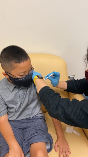 An 8-year-old child receives a shot as part of Pfizer-BioNTech's COVID vaccine clinical trial at Rutgers University. Two out of three participants receive the vaccine; the others receive a placebo.