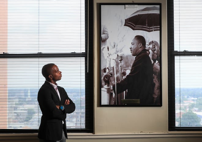 Standing next to a photo of Dr. Martin Luther King speaking at the 1964 March on Frankfort is Terrance Sullivan, the executive director for the Kentucky Commission on Human Rights. "Freedom has always been an expensive thing"  is on a plaque at the bottom of the photo.