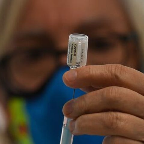 A health worker holds a syringe with a vial of the