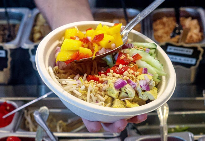 A server adds a homemade mango garnish to a bowl at Eat District, a new DIY-bowl restaurant in Boca Raton. 