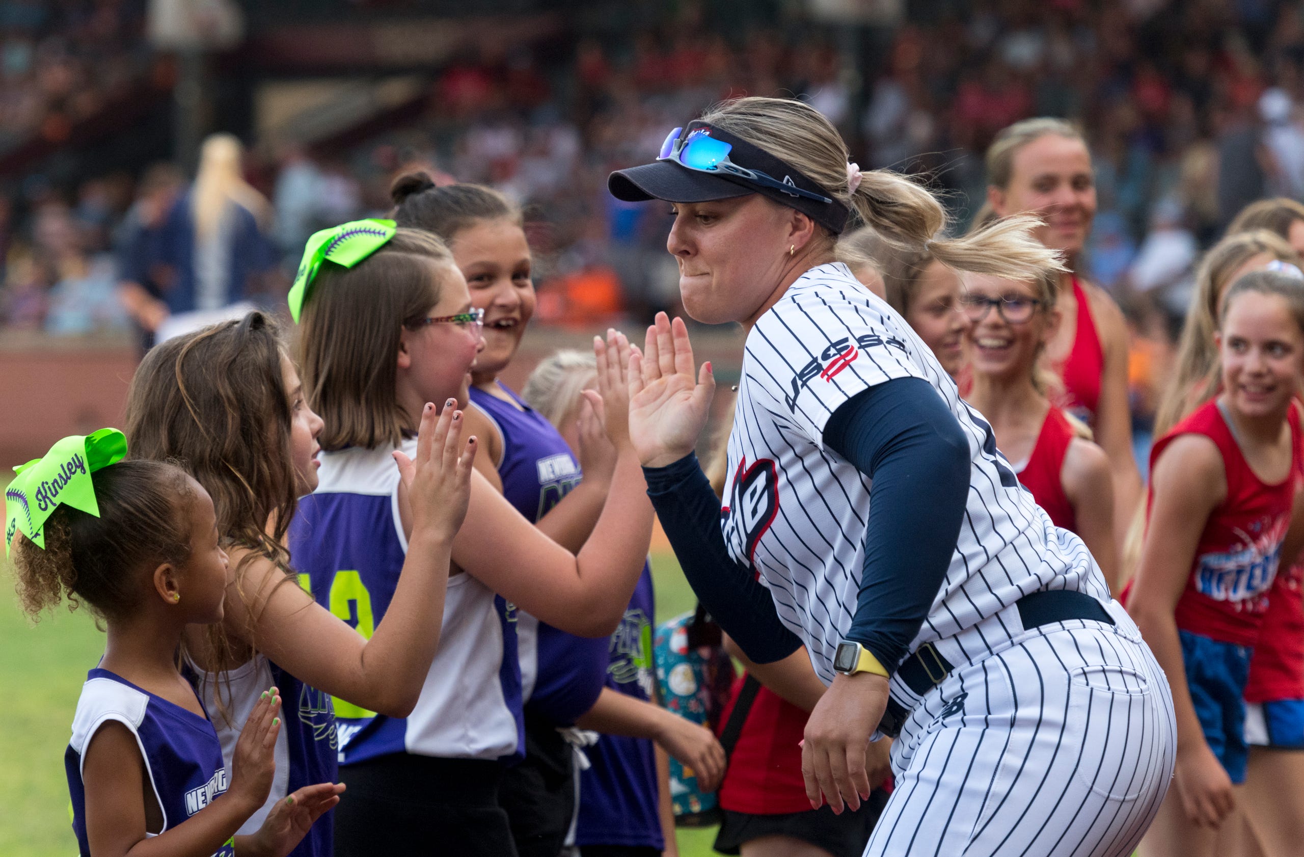 USSSA Pride’s Amanda Lorenz (18) runs down the line giving high fives to the Newburgh Nitro softball team ahead of the exhibition game between USSSA Pride and Team Florida at Bosse Field in Evansville, Ind., Wednesday evening, July 14, 2021.